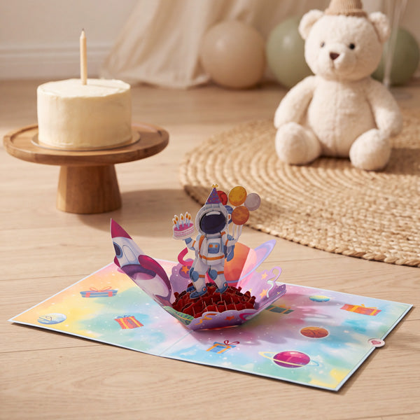 3D pop-up card: Love You to the Moon Birthday, open on the floor beside a birthday cake and teddy bear