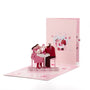 A Toast to Us 3D pop-up card front view: couple toasting at a candlelit table, pink cover behind, everpop