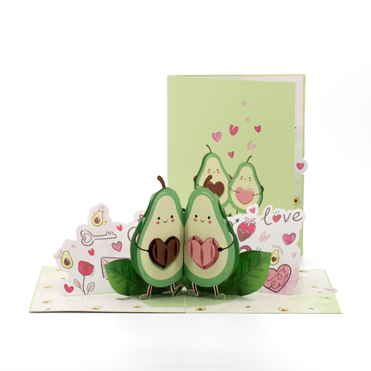 Avocado in Love 3D pop-up card front view: avocado couple holding chocolate hearts, green cover behind, everpop
