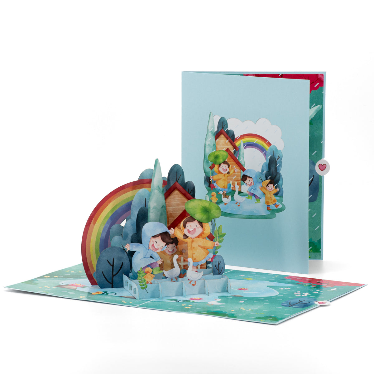 Dancing in the Rain 3D pop-up card front view: kids in raincoats under a rainbow, blue cover behind, everpop