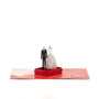 The Wedding Suit & Gown 3D pop-up card angle view: wedding outfits pop-up rising from a red suitcase, everpop